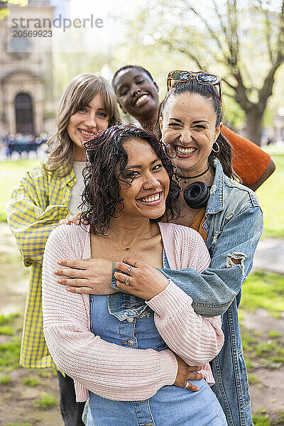 Cheerful multiracial female friends standing in row at park