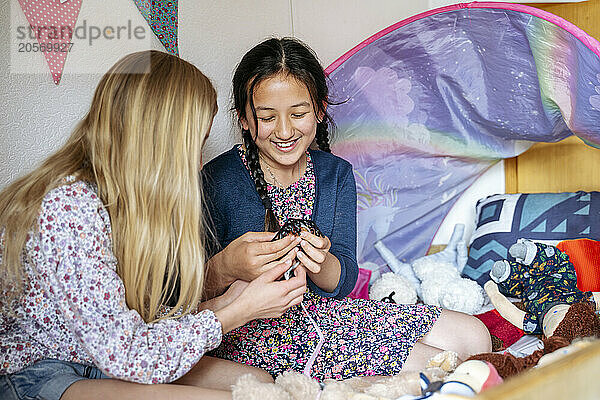 Happy friends playing together on bed at home