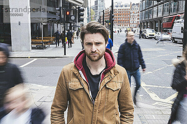 Confused man standing amidst moving pedestrians at street