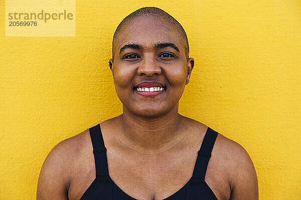 Smiling bald woman in front of yellow wall