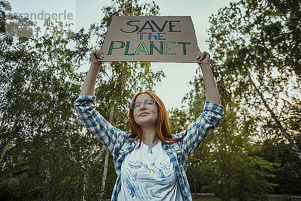 Redhead girl holding protest banner at public park