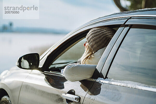 Woman in warm clothes looking out of car window