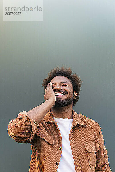 Happy man with eyes closed against gray background