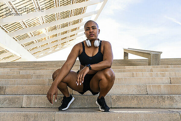 Confident muscular sporty woman crouching on steps