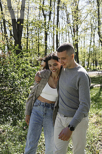 Man with arm around girlfriend walking in park