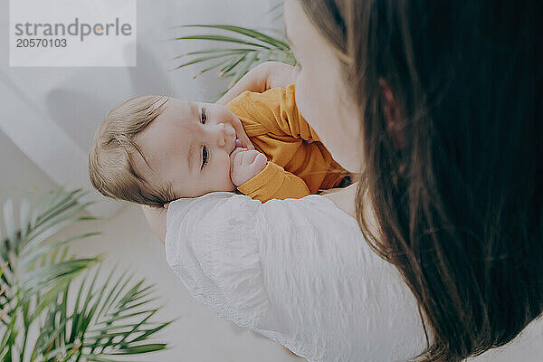 Young mother carrying baby in arms at home