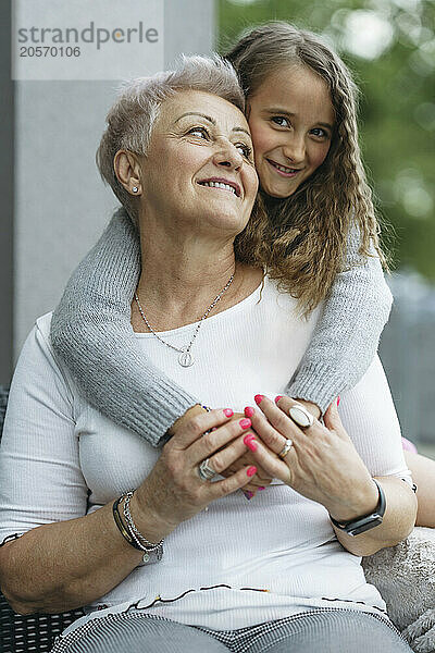 Happy girl embracing grandmother at patio of house