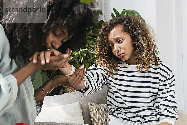 Mother consoling injured daughter kissing her hand