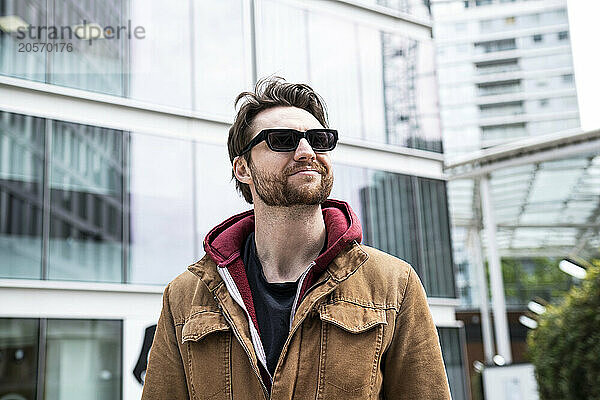 Smiling man wearing sunglasses in front of buildings