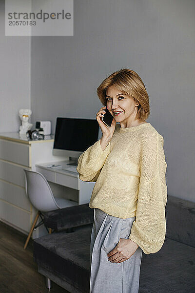 Businesswoman talking on smart phone in living room