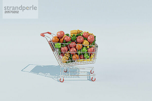 Shopping cart filled with artificial fruits and vegetables against blue background