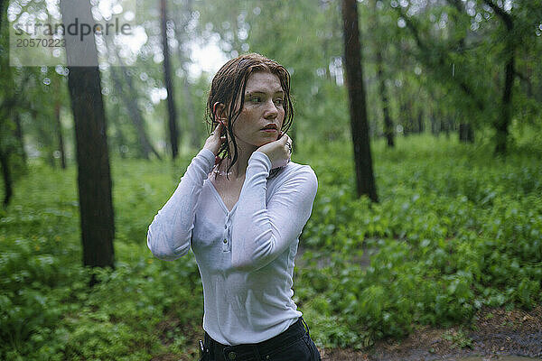 Hipster woman looking away and standing in rain at forest