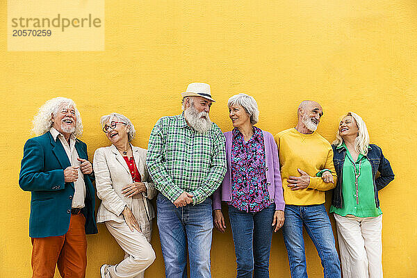 Happy elderly friends leaning on wall