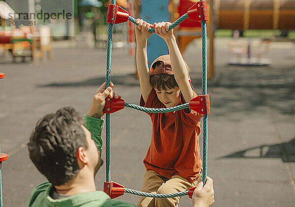 Father helping son to climb at playground