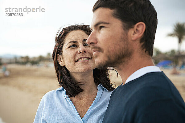 Smiling woman looking at man in front of sky