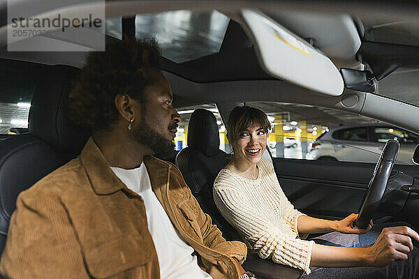 Smiling couple sitting in car at parking garage