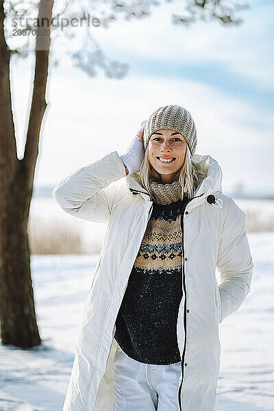 Smiling woman in winter jacket standing on snow