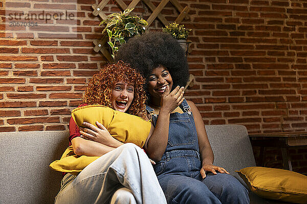 Cheerful multiracial friends spending leisure time watching movie at home