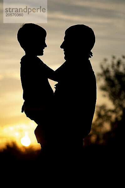 Silhouette of son with father at sunset