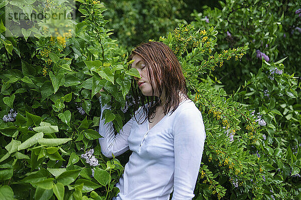 Young woman smelling plant at forest