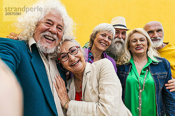 Happy elderly man taking selfie with friends