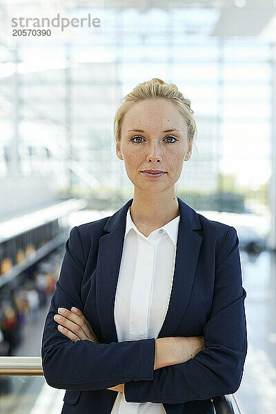 Businesswoman standing with arms crossed at airport lobby