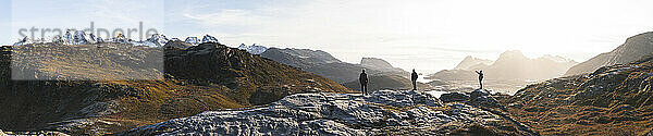 Friends standing on rocks near mountains at Lofoten and Nordic islands in Norway