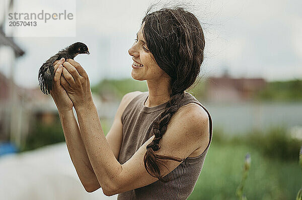 Smiling farmer holding baby chicken