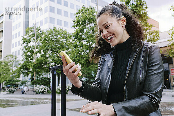 Happy beautiful young woman using smart phone in city