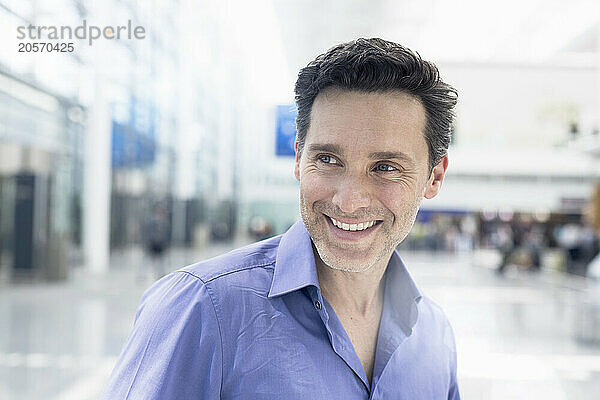 Smiling mature businessman looking away in airport