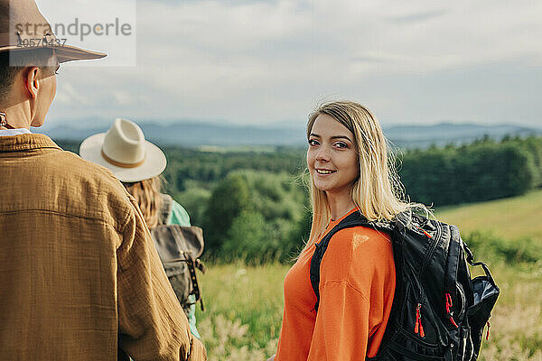 Young woman wearing backpack and hiking with friends on mountain