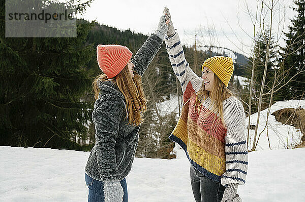 Friends high-fiving on snow field