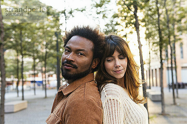 Confident man standing back to back with girlfriend