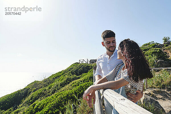 Romantic couple standing near railing at sunny day