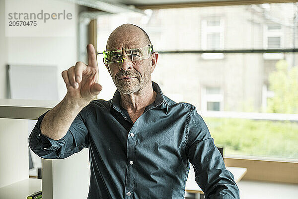 Confident mature businessman wearing smart glasses gesturing at workplace