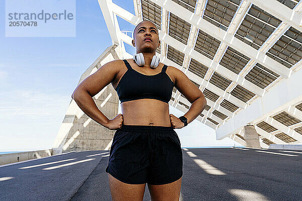 Confident woman with arms akimbo standing on road