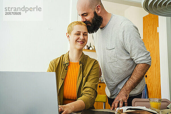 Man kissing smiling freelancer working from home