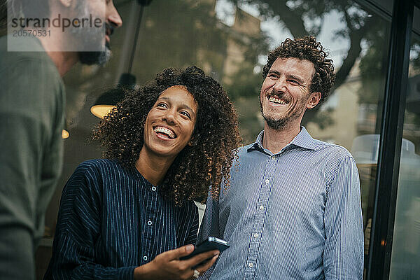 Happy business professionals talking with colleague near cafe