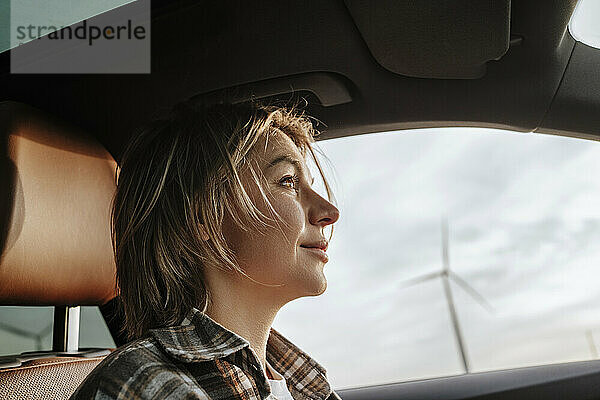 Woman with blond hair siting in car at wind farm