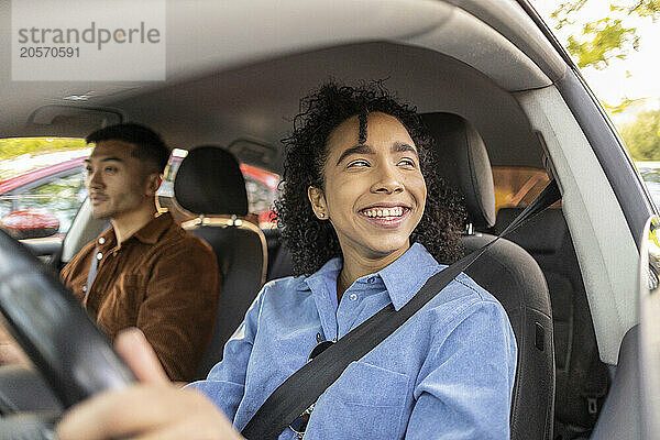 Happy young woman with curly hair sitting with boyfriend in car