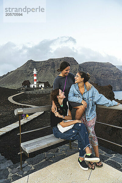 Group of happy young friends in front of Punta Teno Lighthouse in Spain