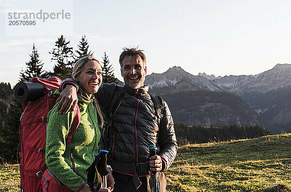 Happy man with arm around girlfriend standing near mountain of Tyrol