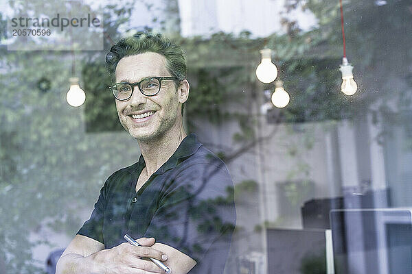 Smiling businessman looking out through office window