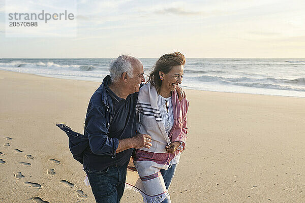 Cheerful senior couple together walking at beach