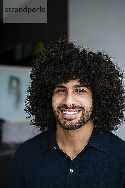 Smiling young handsome curly haired businessman at office