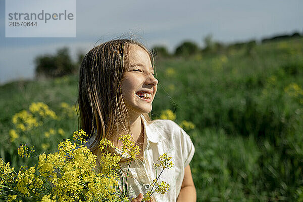 Cheerful girl holding bunch of flowers with eyes closed