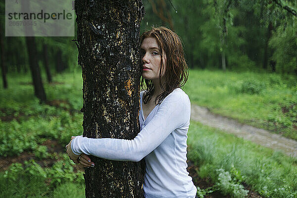 Young woman embracing tree at forest