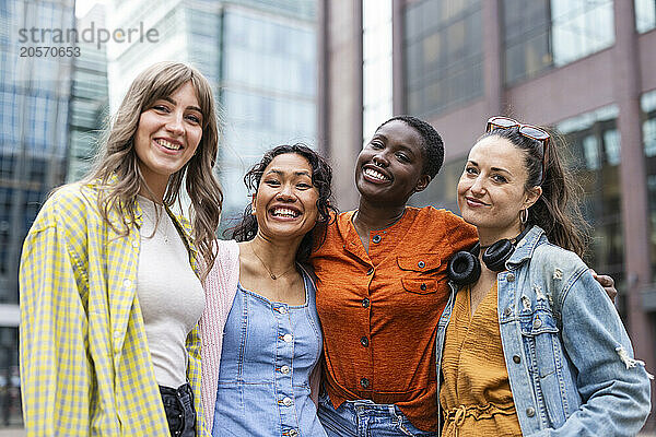 Happy female friends standing in city