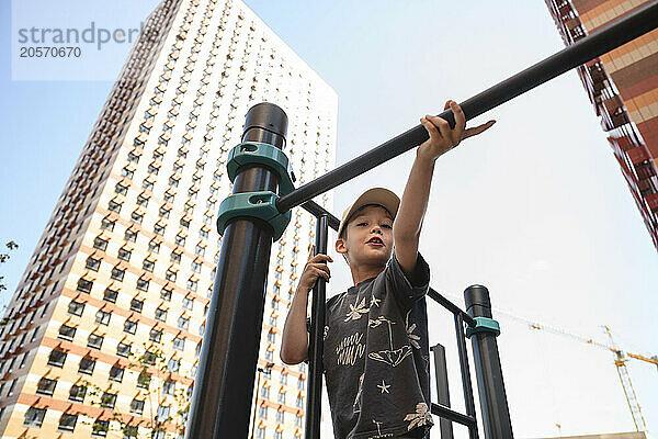 Cute boy playing on pull-bar at playground