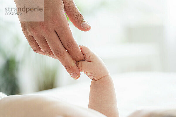 Hand of baby boy holding mother's finger